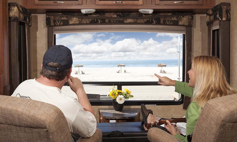 Young Couple Enjoying the Beach View From Their 5th Wheel RV.